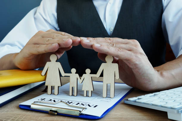 agent protects family figures. life insurance policy on a desk.